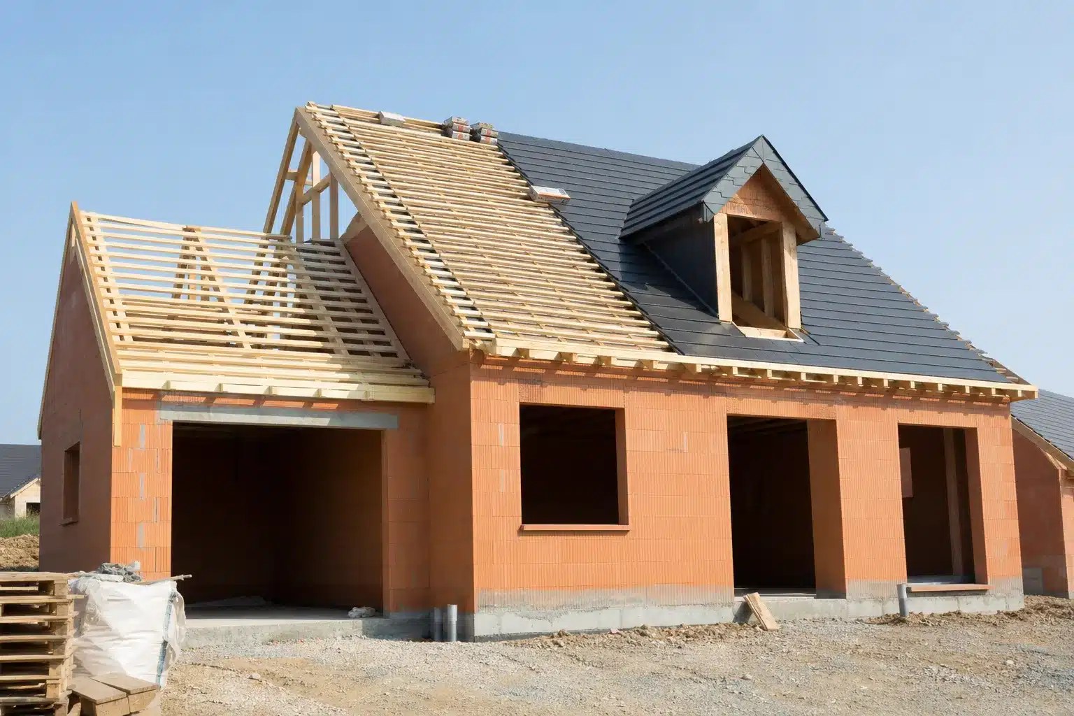 Maison en chantier au stade clos et couvert, avec la toiture posée et les fenêtres installées