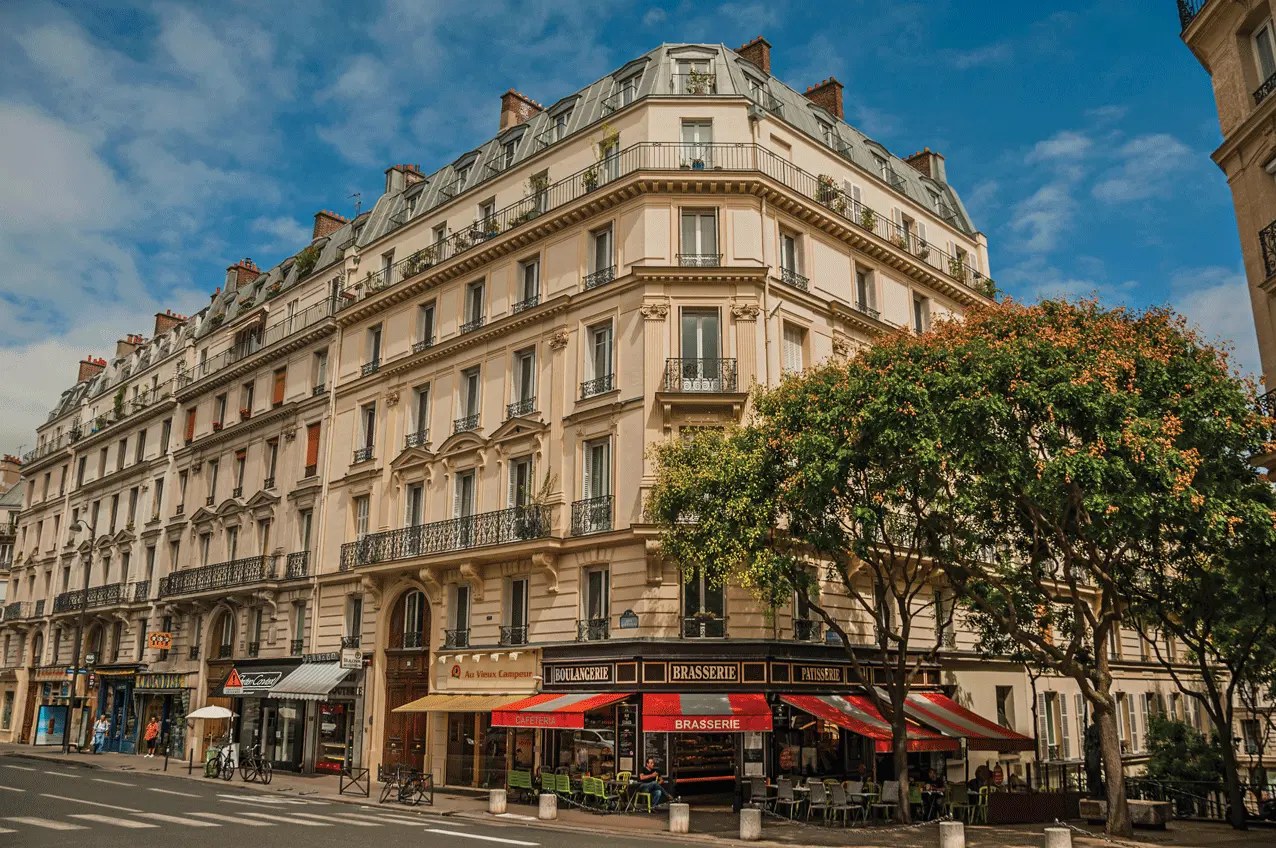 Façade d'immeuble haussmannien en pierre de taille avec balcon filant en fer forgé et toit mansardé en zinc